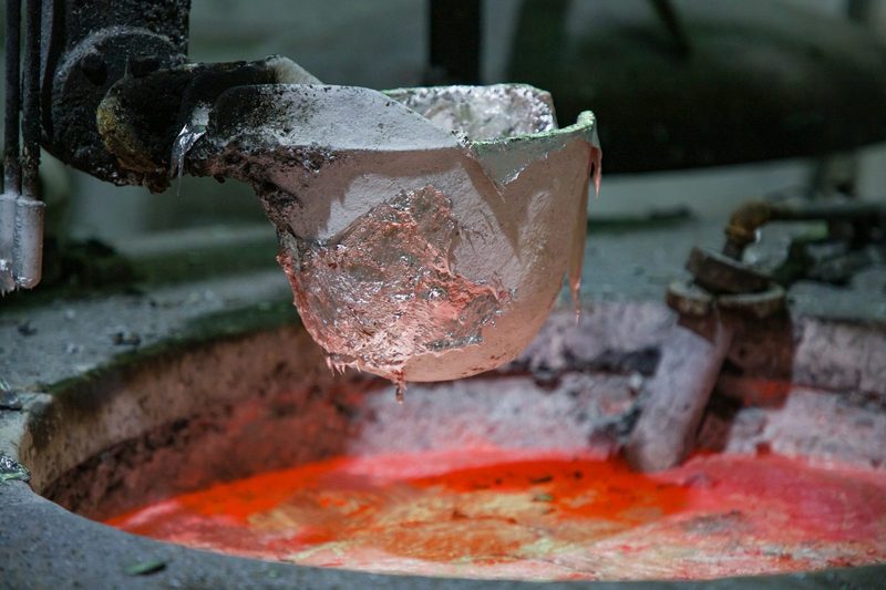 Ladle of molten aluminium being lifted from a furnace, close-up